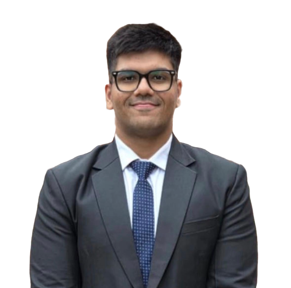 Portrait of Aditya Monga, smiling, wearing glasses and a dark suit with a blue tie.